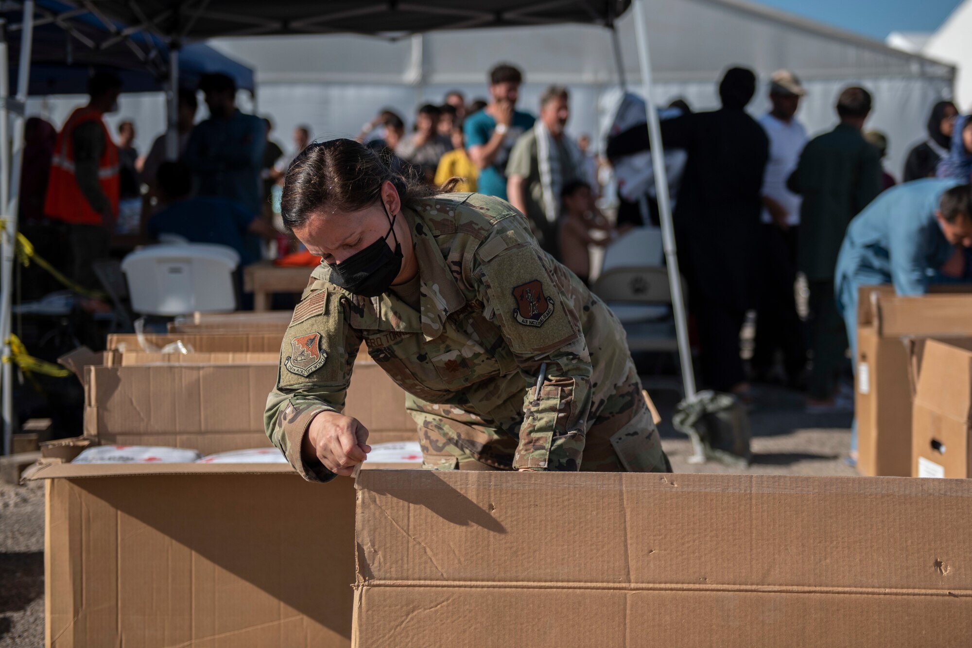 An Airman assigned to Task Force-Holloman helps distribute blankets from the American Red Cross to Afghan refugees at Aman Omid Village at Holloman Air Force Base, New Mexico, Sept. 6, 2021. The Department of Defense, through U.S. Northern Command, and in support of the Department of State and Department of Homeland Security, is providing transportation, temporary housing, medical screening, and general support for at least 50,000 Afghan evacuees at suitable facilities, in permanent or temporary structures, as quickly as possible. This initiative provides Afghan evacuees essential support at secure locations outside Afghanistan. (U.S. Air Force photo by Staff Sgt. Kenneth Boyton)