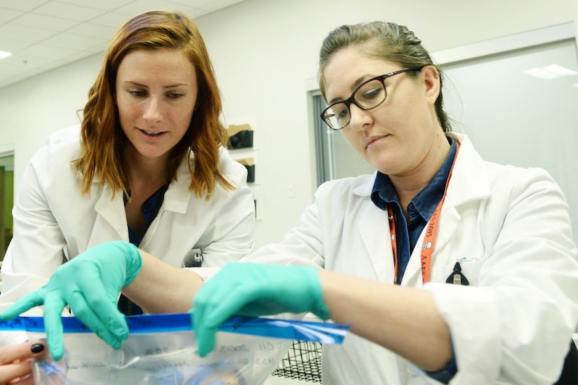 Two women look at something in a plastic bag.