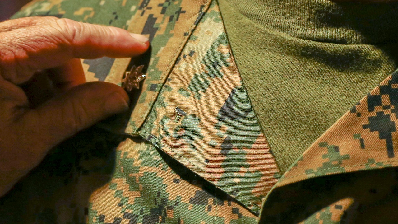 Hand pins rank insignia on uniform