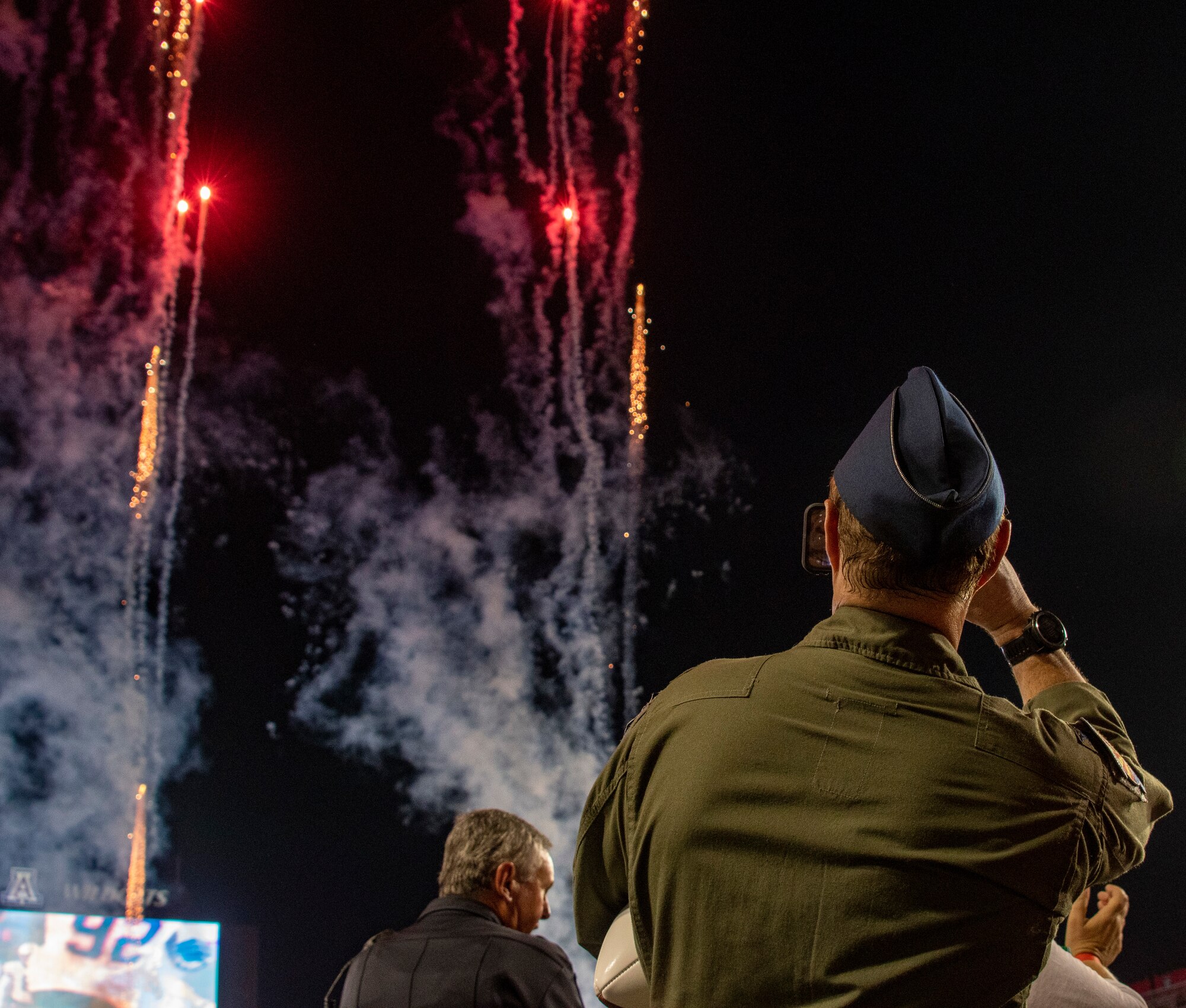 A photo of a military member watching fireworks.