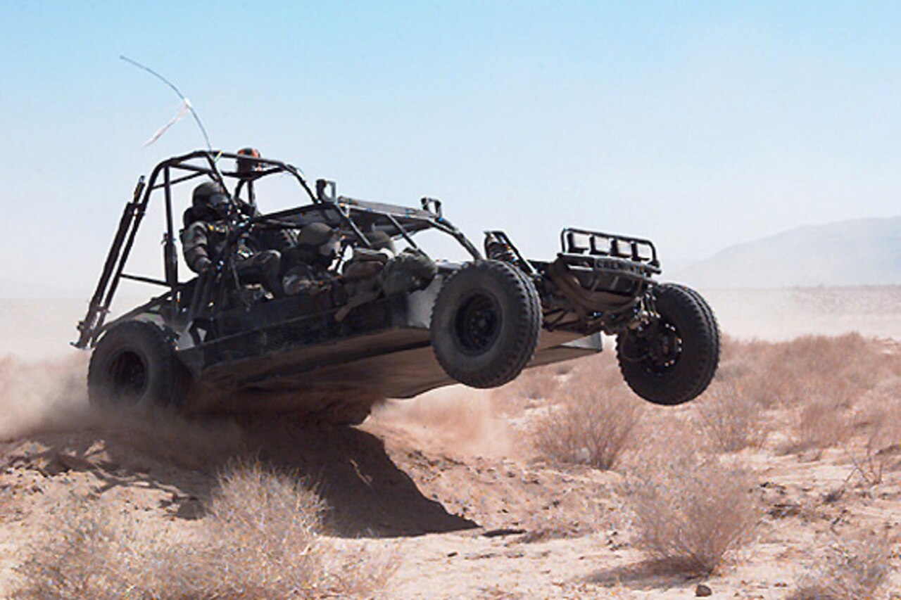 A dune buggy rolls over a sand berm.