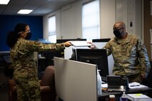 U.S. Air Force Airman 1st Class Helbees Tawadrous, a 354th Contracting Squadron (CONS) contracting specialist, left, hands a document to Tech. Sgt. Justin Williams, the 354th CONS simplified acquisitions team lead, on Eielson Air Force Base, Alaska, Sept. 8, 2021.