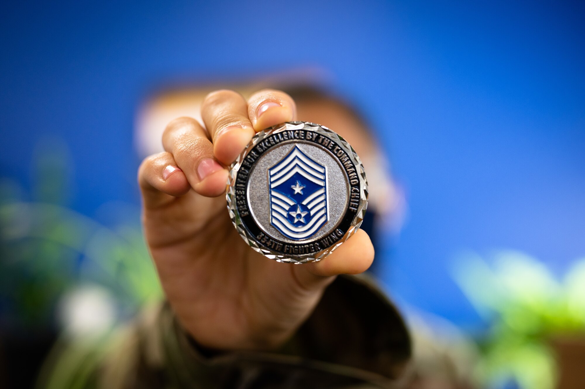 U.S. Air Force Airman 1st Class Helbees Tawadrous, a 354th Contracting Squadron contracting specialist, holds out a 354th Fighter Wing command chief coin on Eielson Air Force Base, Alaska, Sept. 8, 2021.