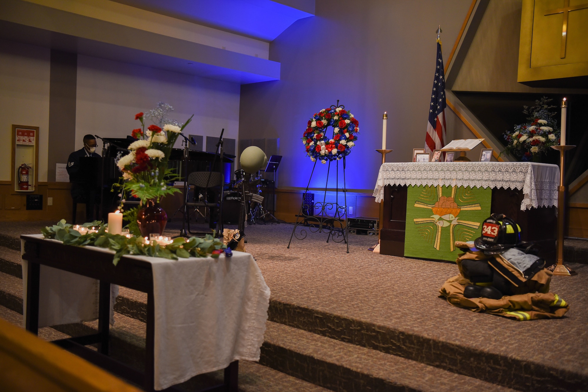 A musician plays the piano in the back of the picture while the front is a stage decorated for the Remembrance ceremony.