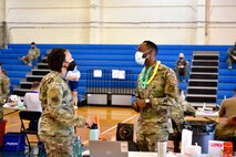 Chief Master Sgt. Sherrone King, 15th Wing command chief, meets with Staff Sgt. Freddie Smith, 15th Operational Medical Squadron aerospace service technician, while working at a mass COVID-19 vaccination clinic at Joint Base Pearl Harbor-Hickam, Hawaii, Sept. 8, 2021. Vaccines were prepared and administered in the gym by medical personnel for approximately 13 hours. (U.S. Air Force photo by 1st Lt. Benjamin Aronson)