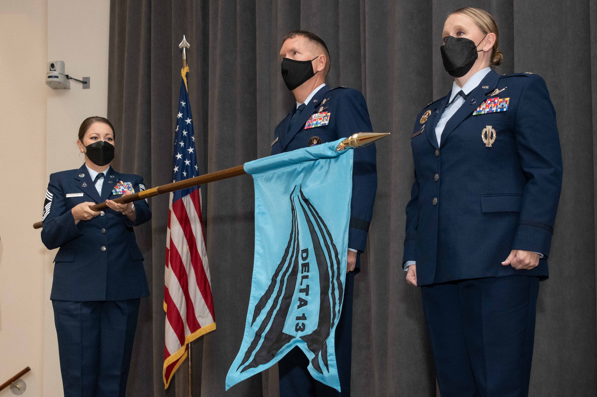 Brig. Gen. Shawn Bratton, Space Training and Readiness Command commander, and Col. Niki Lindhorst, Air University space chair, stand at attention as Chief Master Sgt. Esther Sanford unfurls the Space Delta 13 flag during the unit’s activation ceremony at Officer Training School, Sep. 13, 2021.