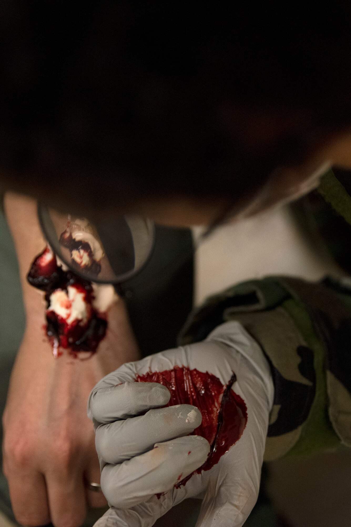 Senior Airman Kenyetta Oglesbe adds fake blood to a broken wrist fracture moulage prior to a training scenario