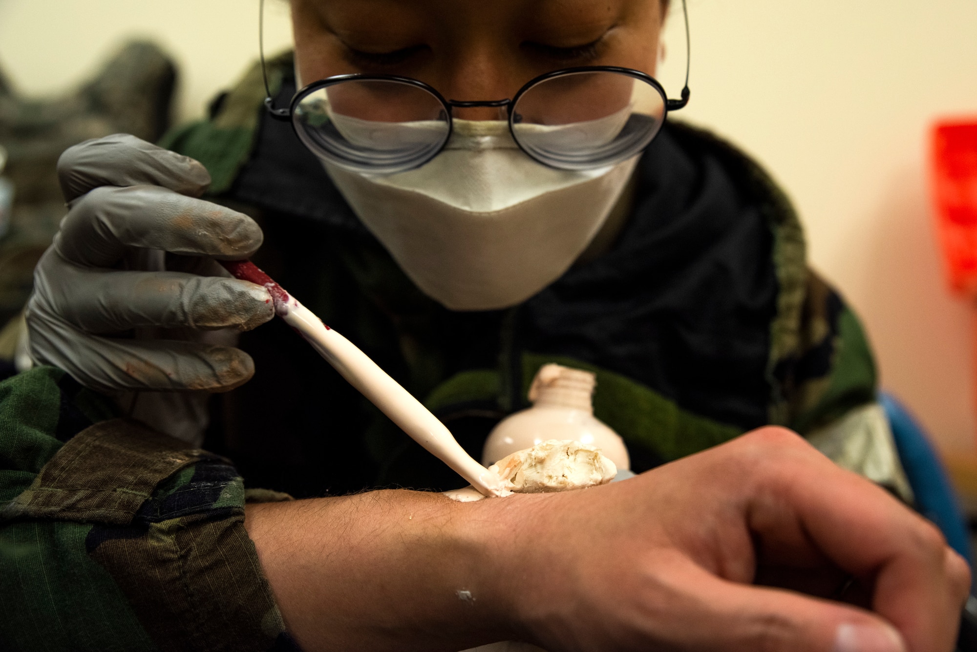 Senior Airman Kenyetta Oglesbe prepares a wrist fracture moulage for a member prior to a training scenario