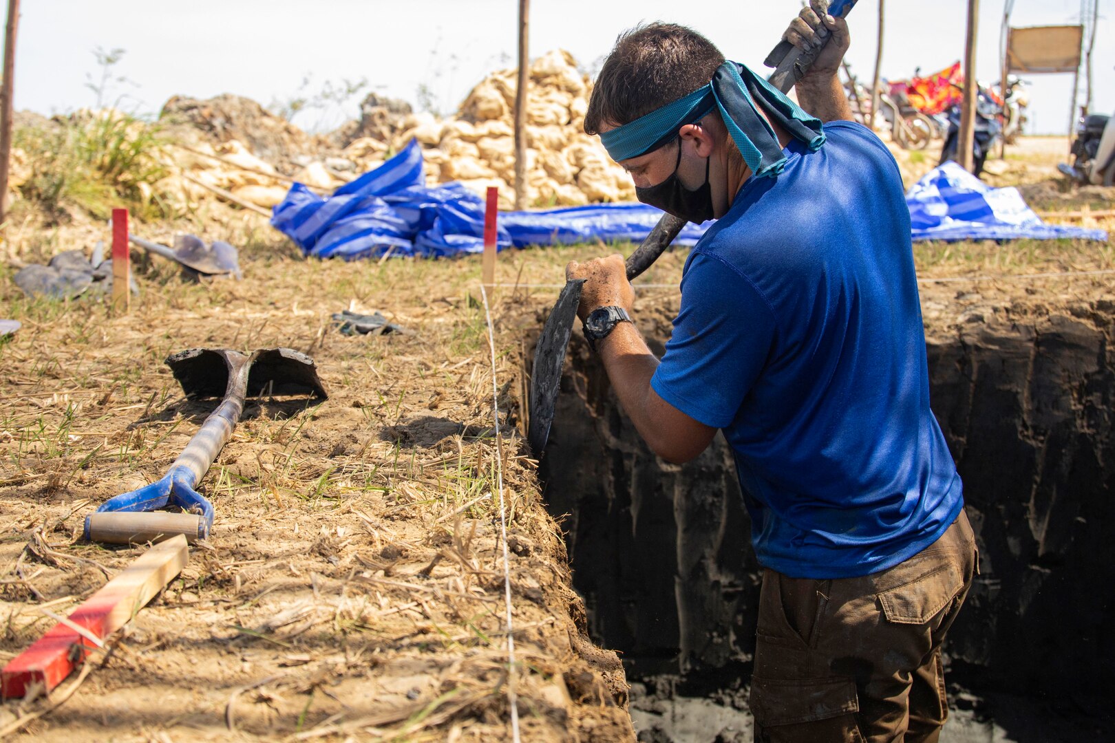 A man stands in a pit and shovels dirt.