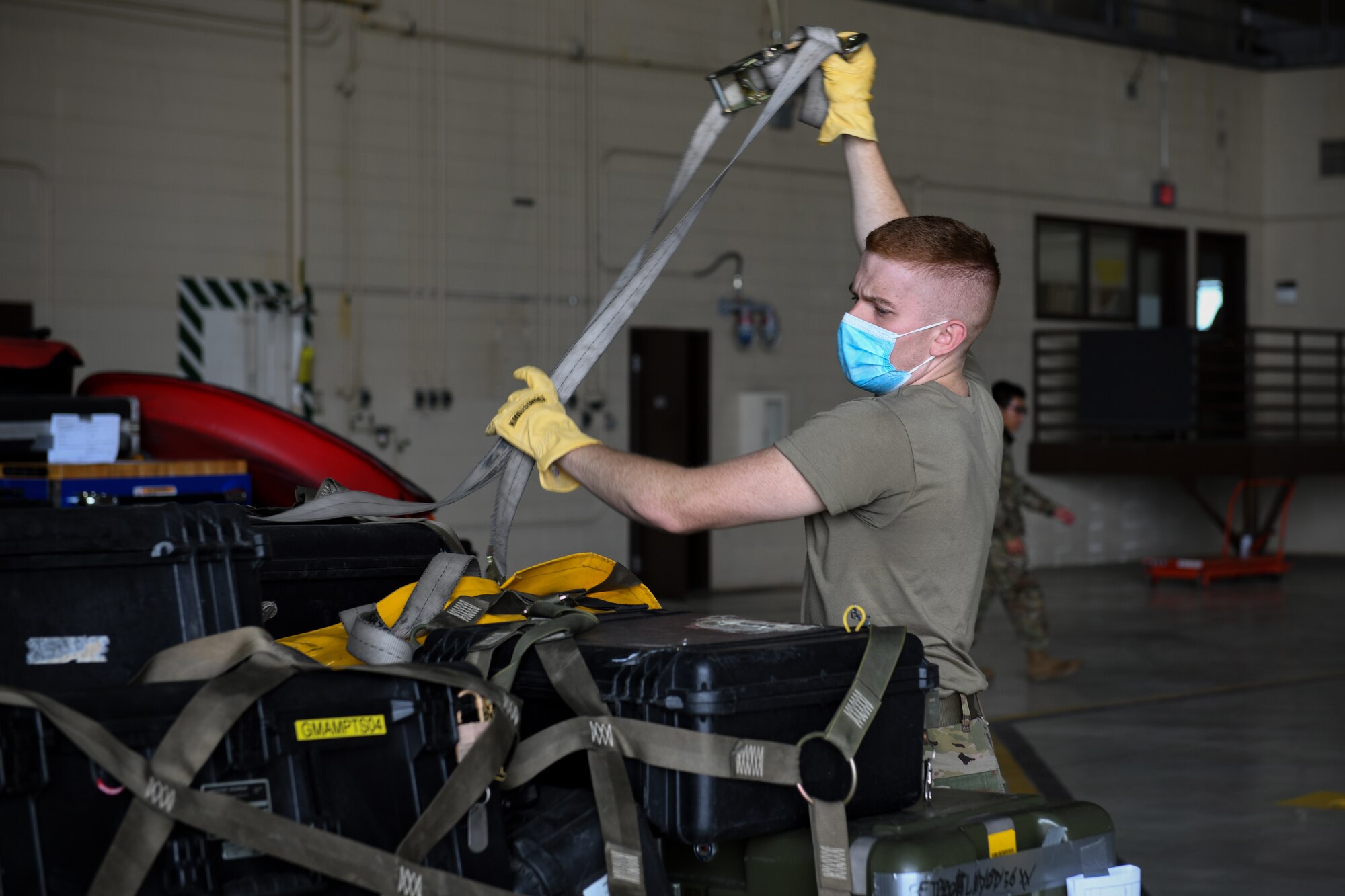 An Airman from 319th Aircraft Maintenance Squadron unfastens the lashing belts off of a pallet during an exercise on Grand Forks Air Force Base, N.D., Aug. 18, 2021. This exercise gave GFAFB Airmen hands-on experience building pallets, coordinating hazardous materials declarations and learning how to meet the mission despite limiting factors. (U.S. Air Force photo by Airman 1st Class Ashley Richards)