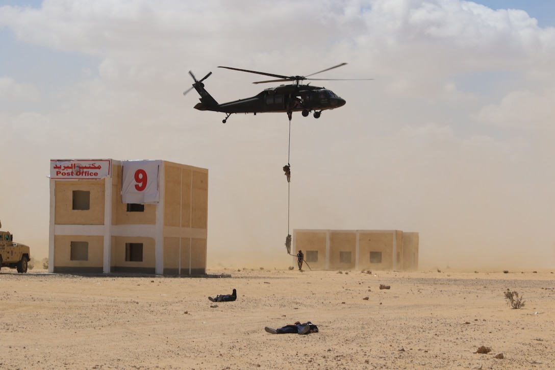 Partner nations Special Operations Forces fast-rope into a small village during Military Operations in Urban Terrain (MOUT) rehearsals at Bright Star 21, Sept. 11, in Mohamed Naguib Military Base, Egypt. Fast-roping works well for insertion and extraction operations in environments when the helicopter cannot touch down. BS21 is a multilateral exercise allowing full-spectrum military, interagency and ministerial response to near-peer and irregular warfare threats.  (U.S. Army photo by Staff Sgt. Dean Gannon)