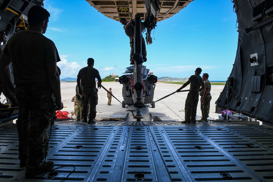 Soldiers prepare to load a helicopter into a large aircraft.