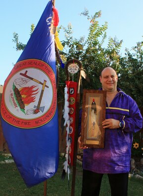 Photo of man holding a shadow box and standing next to a flag