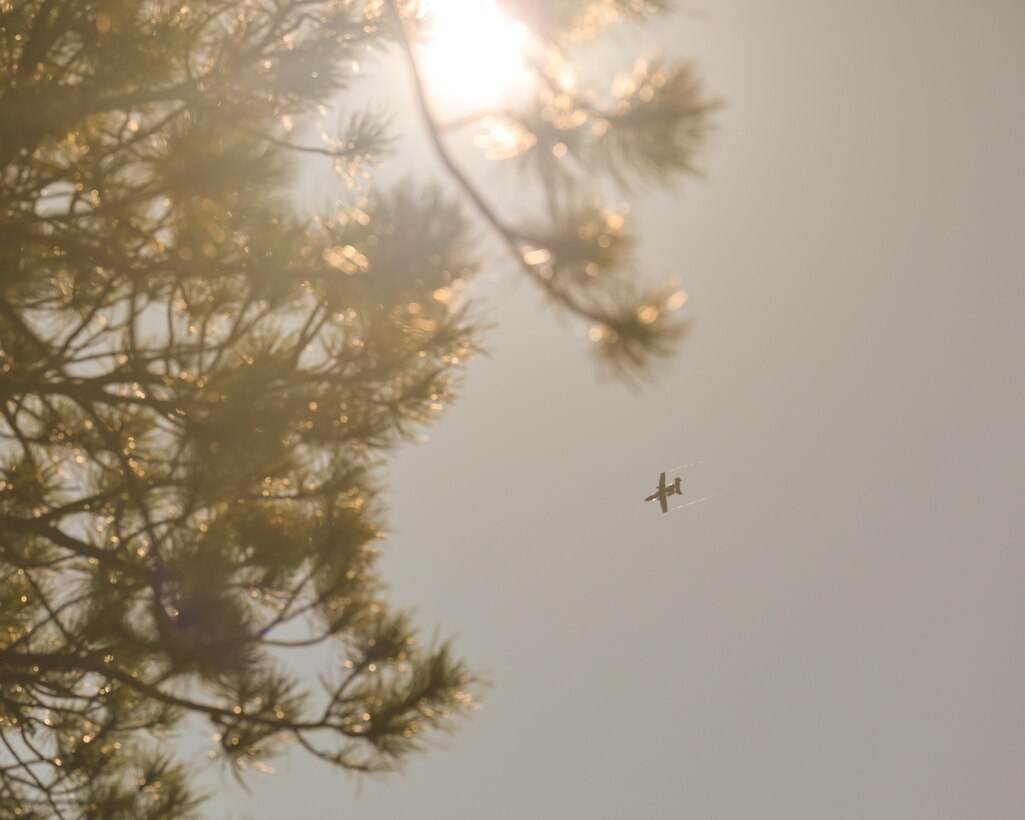 two military members hang from helicopter