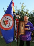 Photo of man holding a shadow box and standing next to a flag