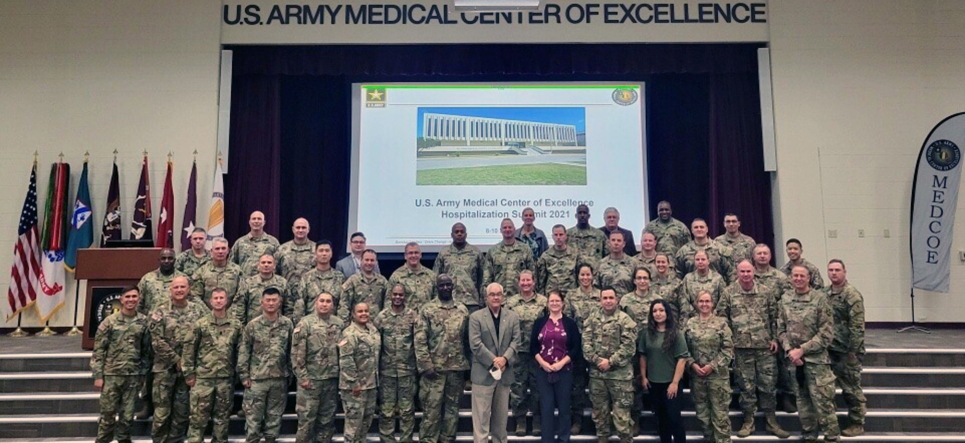 Fully-vaccinated in-person attendees, who wore masks during the three-day hospitalization summit as an extra COVID-19 precaution, pose for a quick “mask-off” group photo with J.M. Harmon III (center), deputy to the commanding general, U.S. Army Medical Center of Excellence, on Sept. 10 in Blesse Auditorium at Joint Base San Antonio-Fort Sam Houston.
