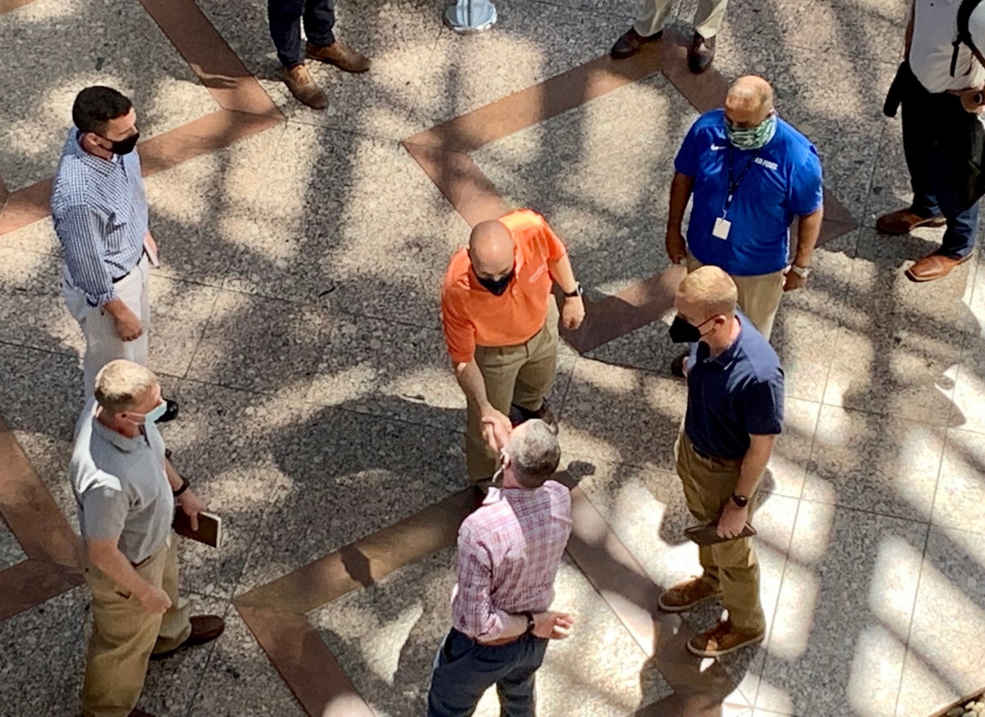 Aerial shot of group of people standing, two men are shaking hands