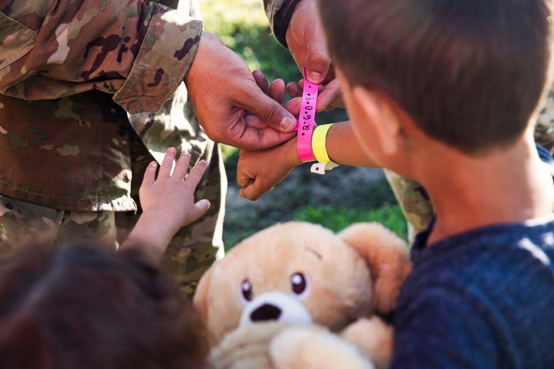 A soldiers secures a wristband on a child.