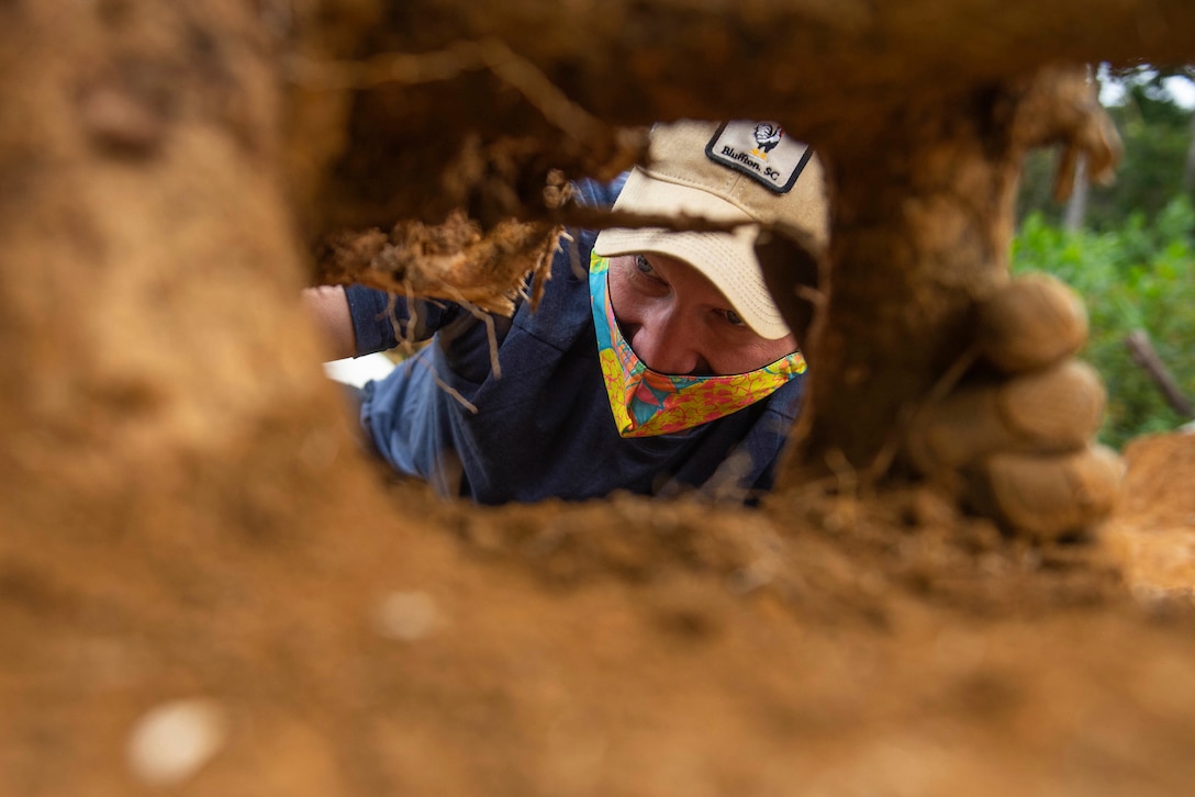 An airman removes dirt from the ground.