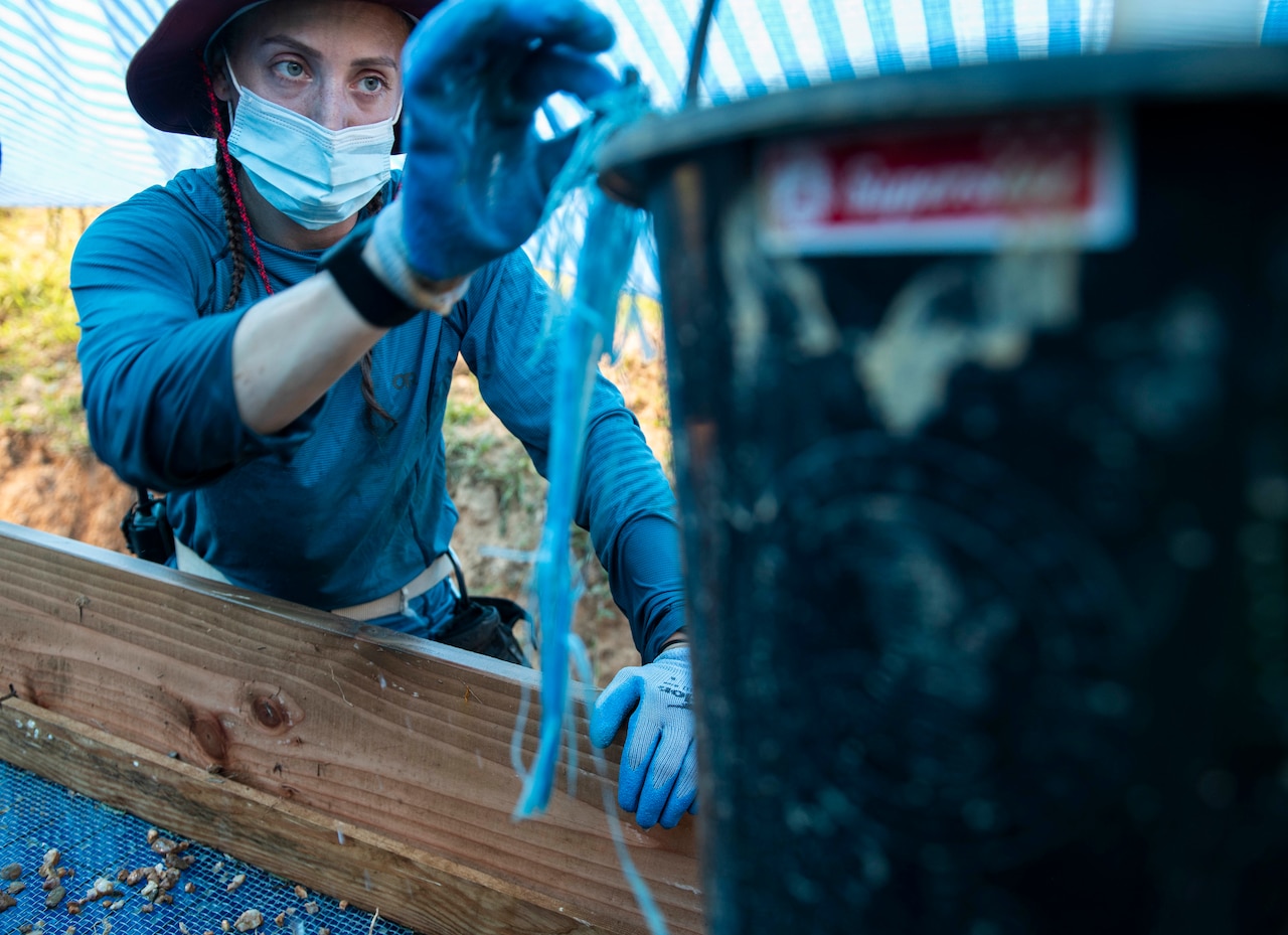 A solider puts materials in a bucket.