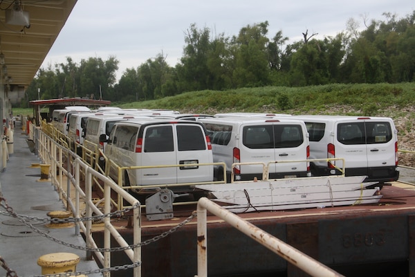 Passenger vans wait on a barge before a quarter boat departs with the Mat Sinking Unit (MSU). The vans will transport crew members to and from job sites along the Mississippi River.