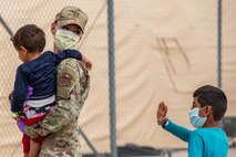 An Airman attached to Task Force-Holloman aids Afghan children as they arrive to Holloman Air Force Base, New Mexico, Sept. 2, 2021. The Department of Defense, through U.S. Northern Command, and in support of the Department of State and Department of Homeland Security, is providing transportation, temporary housing, medical screening, and general support for up to 50,000 Afghan evacuees at suitable facilities, in permanent or temporary structures, as quickly as possible. This initiative provides Afghan evacuees essential support at secure locations outside Afghanistan. (U.S. Army photo by Pfc. Anthony X. Sanchez)
