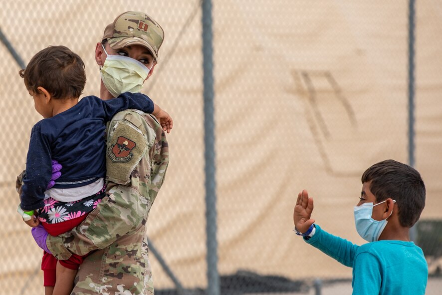 An Airman attached to Task Force-Holloman aids Afghan children as they arrive to Holloman Air Force Base, New Mexico, Sept. 2, 2021. The Department of Defense, through U.S. Northern Command, and in support of the Department of State and Department of Homeland Security, is providing transportation, temporary housing, medical screening, and general support for up to 50,000 Afghan evacuees at suitable facilities, in permanent or temporary structures, as quickly as possible. This initiative provides Afghan evacuees essential support at secure locations outside Afghanistan. (U.S. Army photo by Pfc. Anthony X. Sanchez)
