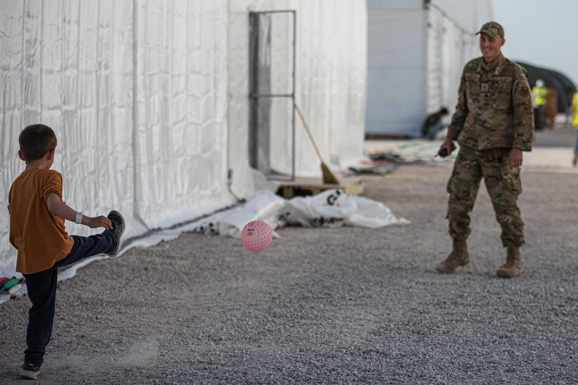 An Airman attached to Task Force-Holloman plays with an Afghan evacuee at Aman Omid Village on Holloman Air Force Base, New Mexico, Sept. 5, 2021. The Department of Defense, through U.S. Northern Command, and in support of the Department of State and Department of Homeland Security, is providing transportation, temporary housing, medical screening, and general support for at least 50,000 Afghan evacuees at suitable facilities, in permanent or temporary structures, as quickly as possible. This initiative provides Afghan evacuees essential support at secure locations outside Afghanistan. (U.S. Army photo by Pfc. Anthony Sanchez)