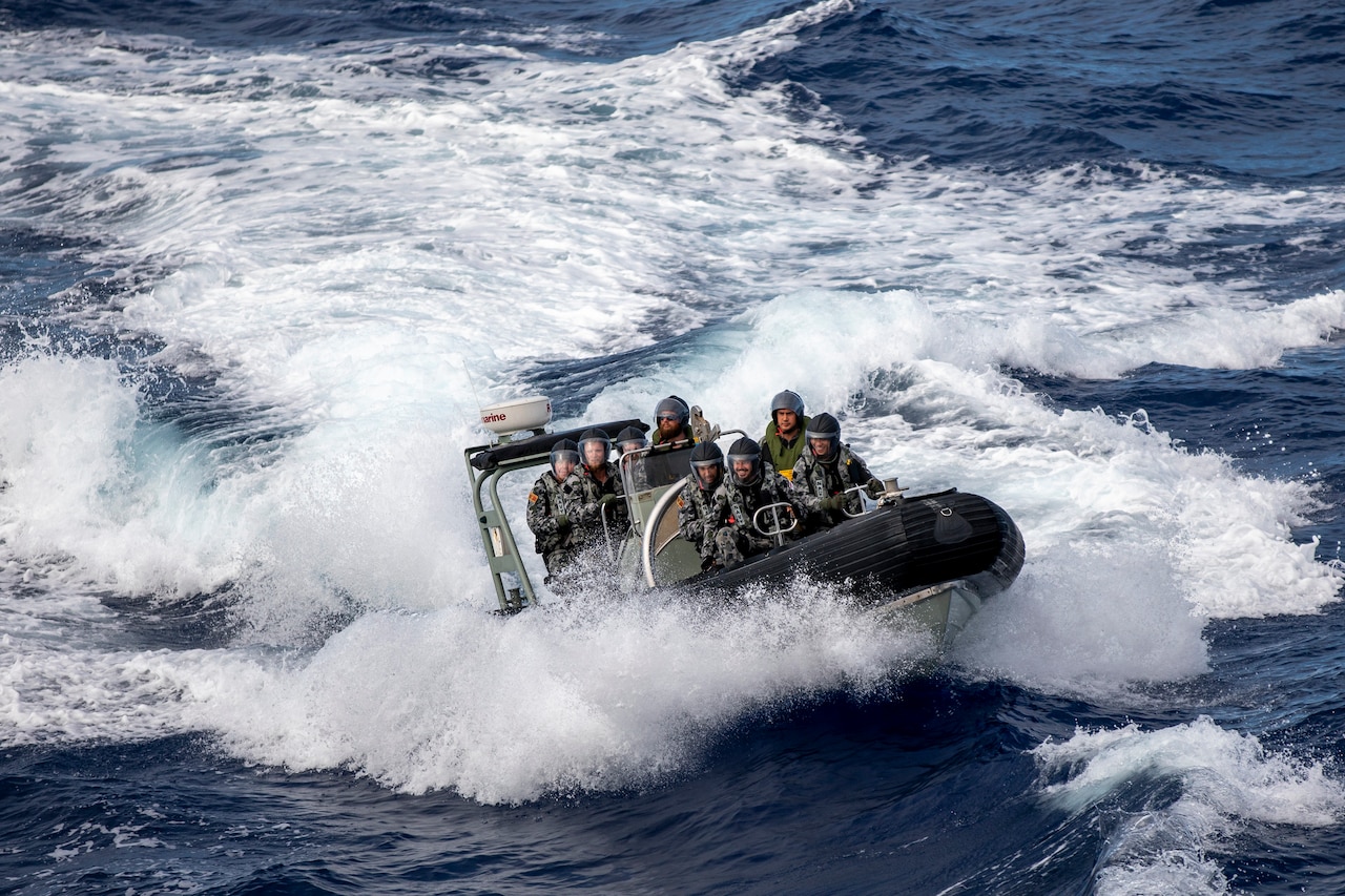 Sailors in a small boat crest through the waves.