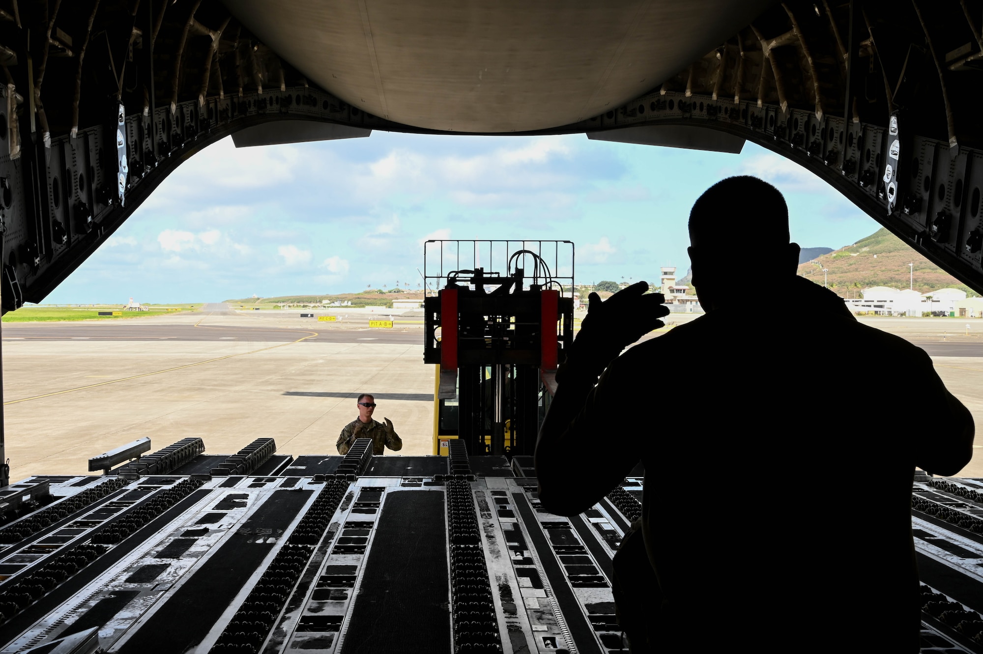 U.S. Air Force Tech. Sgt. James Delgadillo, 58th Airlift Squadron instructor loadmaster, directs a forklift at Marine Corps Base Hawaii, Sept. 9, 2021. More than 30,000 pounds of MQ-9 Reaper assets were loaded in support of exercise Agile Combat Employment Reaper. (U.S. Air Force photo by Airman 1st Class Kayla Christenson)