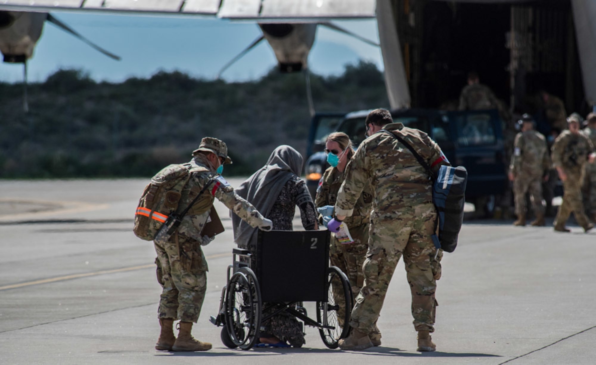 Airmen from Task Force-Holloman assist an Afghan evacuee into a wheelchair on the ramp at Holloman Air Force Base, New Mexico, Aug. 31, 2021. The Department of Defense, through U.S. Northern Command, and in support of the Department of State and Department of Homeland Security, is providing transportation, temporary housing, medical screening, and general support for up to 50,000 Afghan evacuees at suitable facilities, in permanent or temporary structures, as quickly as possible. This initiative provides Afghan evacuees essential support at secure locations outside Afghanistan. (U.S. Air Force photo by Staff Sgt. Kenneth Boyton)