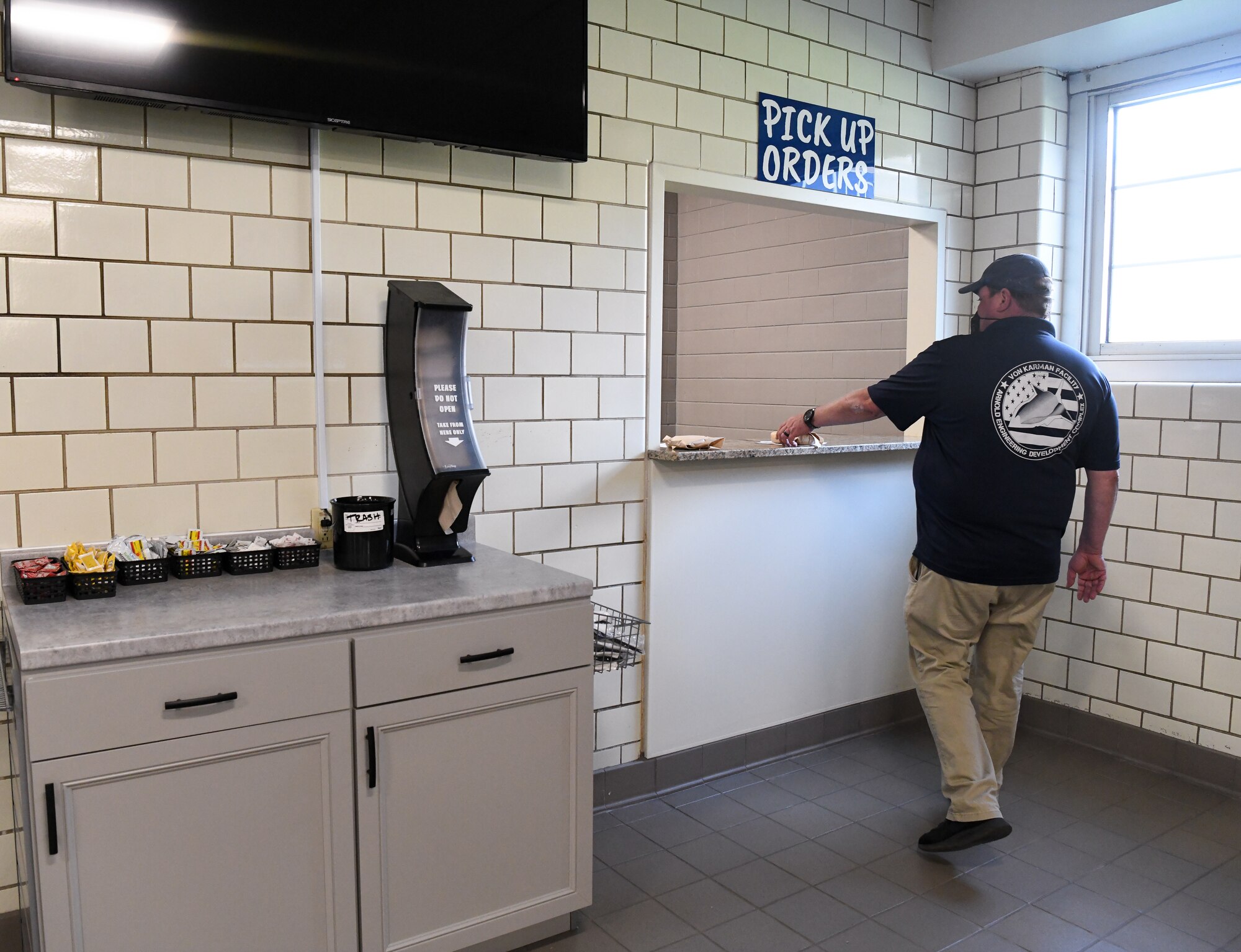 Greg Crabtree, an Arnold Engineering Development Complex test operations engineer, picks up his order, Sept. 9, 2021, at Café 100 on Arnold Air Force Base, Tenn. As part of the renovation to the dining facility, all food preparation was moved into the kitchen area and made-to-order items are delivered at the pick-up window. (U.S. Air Force photo by Jill Pickett)