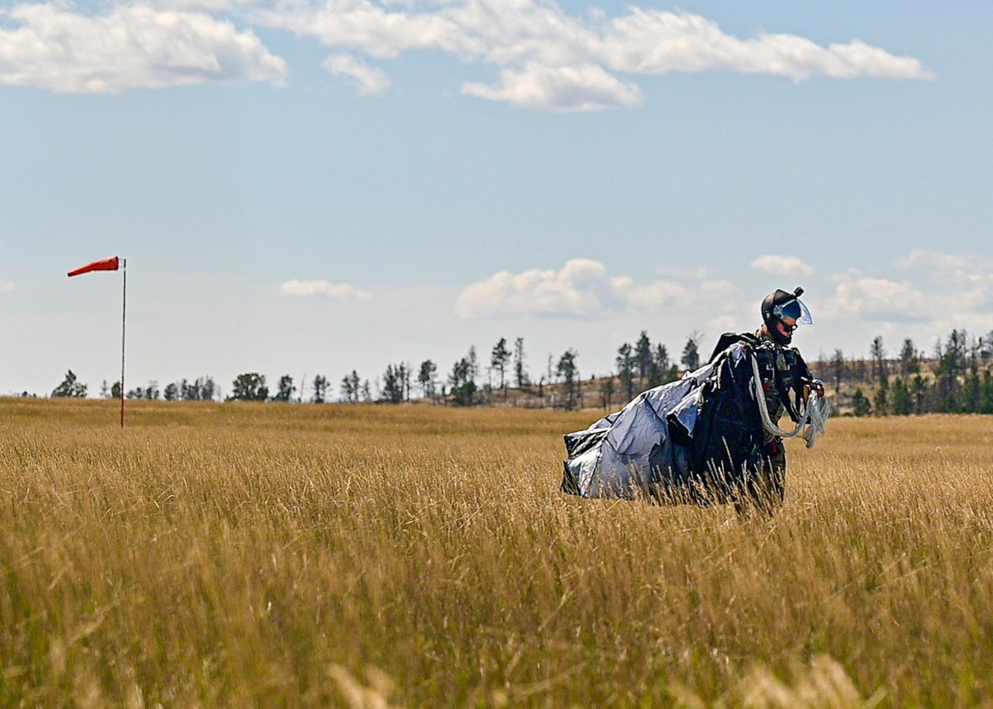 Airman standing in field packing parachute