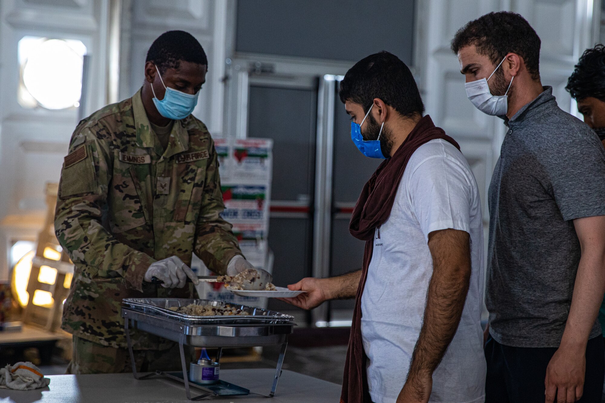 Airmen attached to Task Force-Holloman feed with Afghan personnel in support of Operation Allies Welcome on Aman Omid Village at Holloman Air Force Base, New Mexico, Sept. 12, 2021. The Department of Defense, through U.S. Northern Command, and in support of the Department of State and Department of Homeland Security, is providing transportation, temporary housing, medical screening, and general support for at least 50,000 Afghan evacuees at suitable facilities, in permanent or temporary structures, as quickly as possible. This initiative provides Afghan evacuees essential support at secure locations outside Afghanistan. (U.S. Army photo by Pfc. Anthony Sanchez)