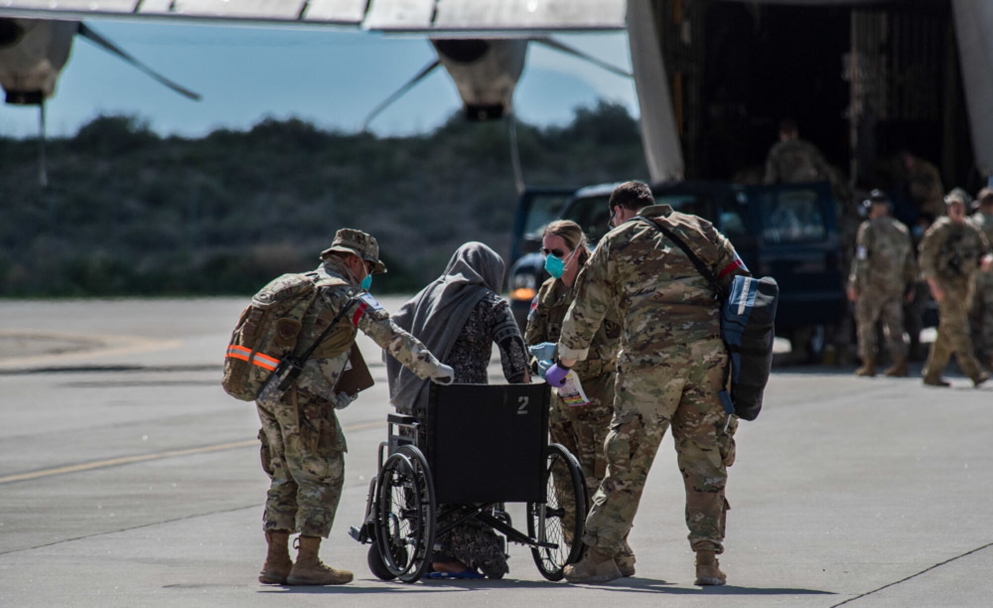 Airmen from Task Force-Holloman assist an Afghan evacuee into a wheelchair on the ramp at Holloman Air Force Base, New Mexico, Aug. 31, 2021. The Department of Defense, through U.S. Northern Command, and in support of the Department of State and Department of Homeland Security, is providing transportation, temporary housing, medical screening, and general support for up to 50,000 Afghan evacuees at suitable facilities, in permanent or temporary structures, as quickly as possible. This initiative provides Afghan evacuees essential support at secure locations outside Afghanistan. (U.S. Air Force photo by Staff Sgt. Kenneth Boyton)