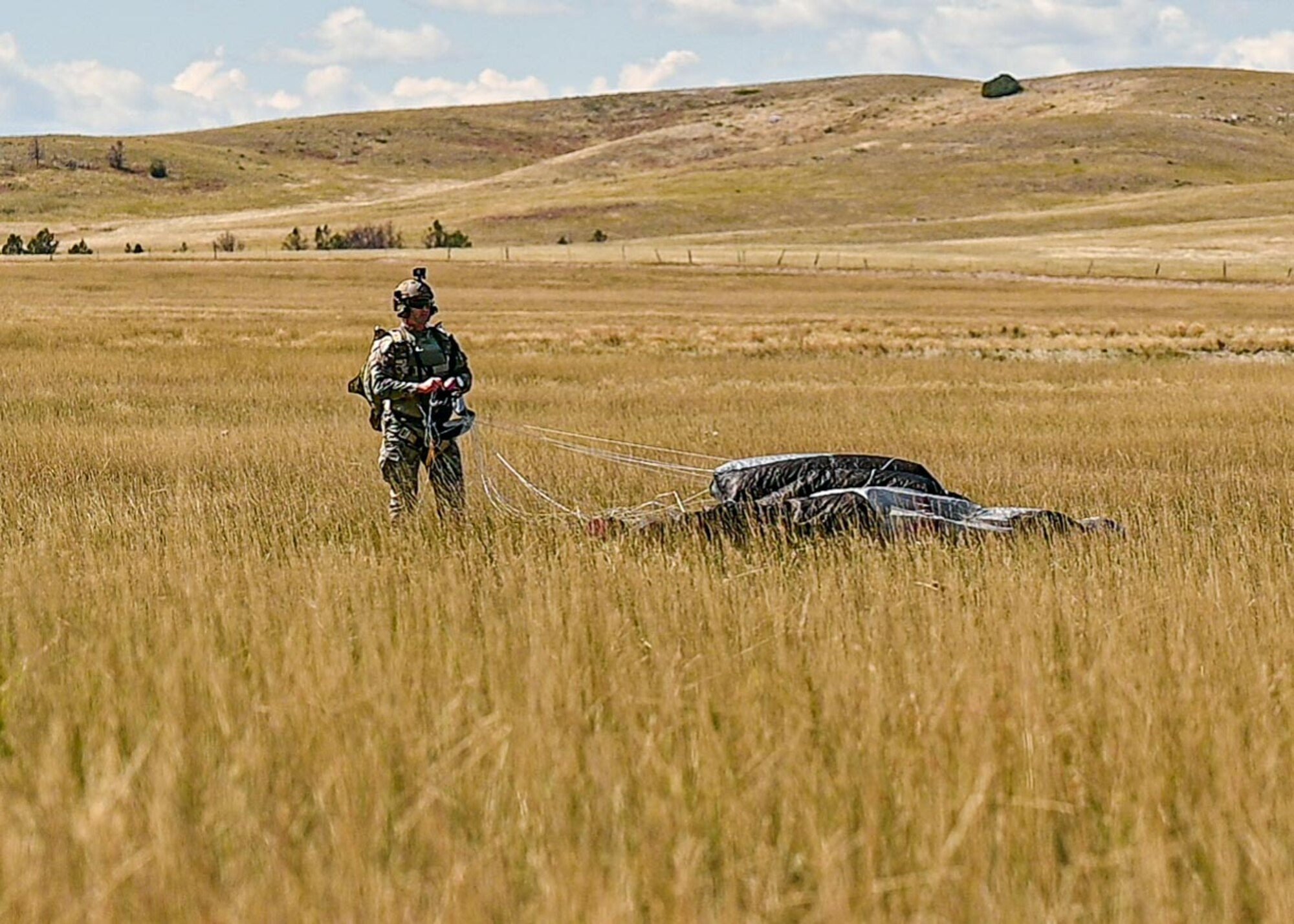 Airman standing in field packing parachute