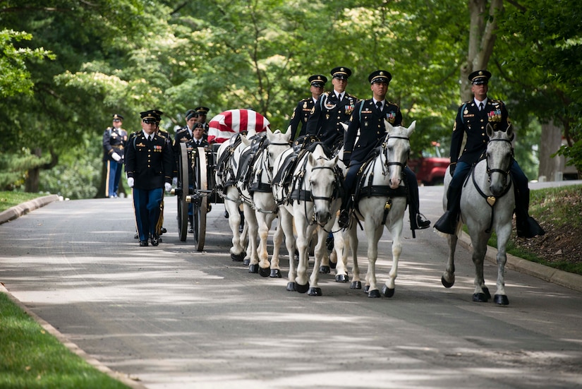 Soldiers on horses draw a casket.