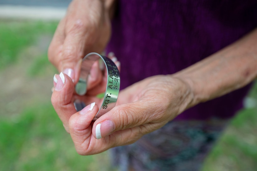 A woman holds a pow/mia bracelet in her hands.