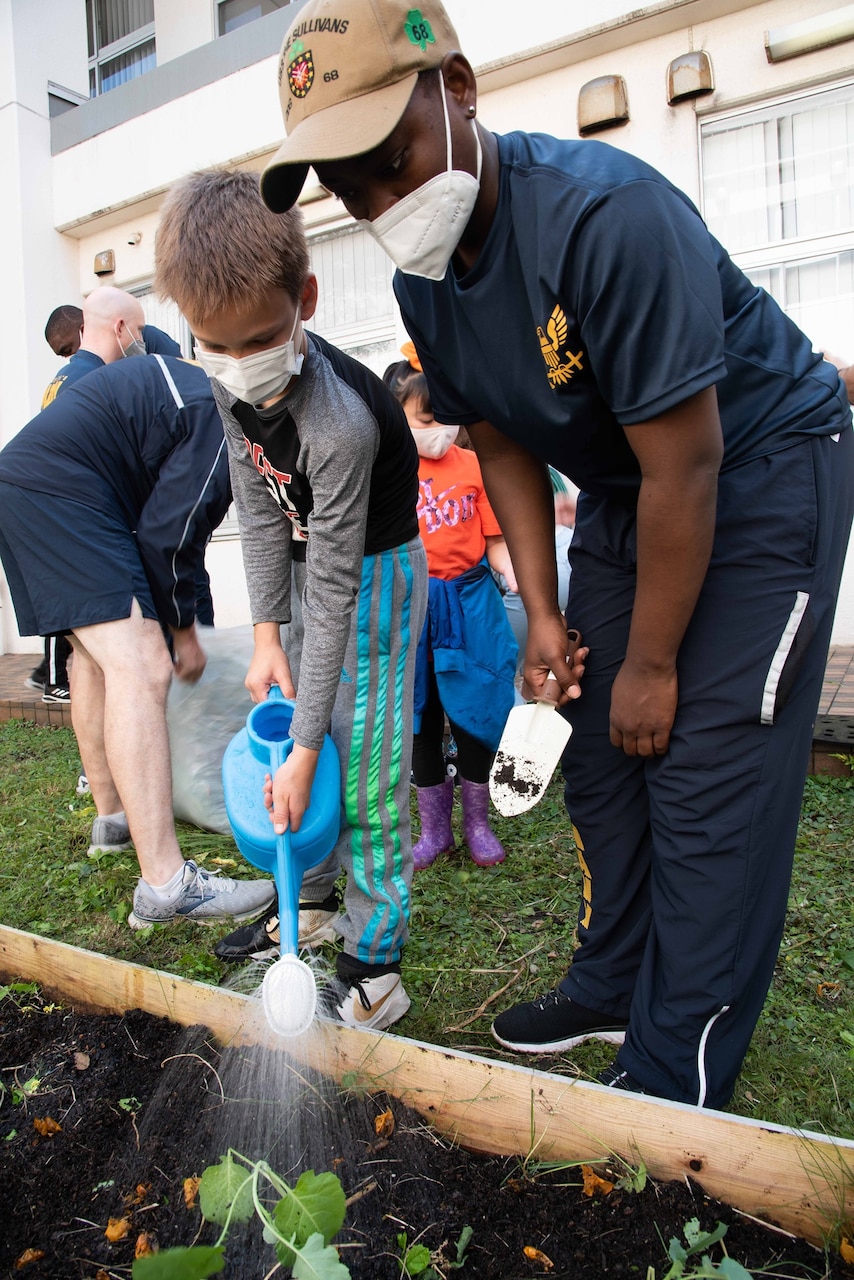 YOKOSUKA, Japan (Sept. 15, 2021) — Electrician's Mate 3rd Class Sashana Oakley, attached to the Arleigh Burke-class guided missile destroyer USS The Sullivans (DDG 68), waters seeds with a student from the Sullivans School onboard Commander, Fleet Activities Yokosuka (CFAY) while participating in the school’s gardening project. For more than 75 years, CFAY has provided, maintained, and operated base facilities and services in support of the U.S. 7th Fleet's forward-deployed naval forces, tenant commands, and thousands of military and civilian personnel and their families.