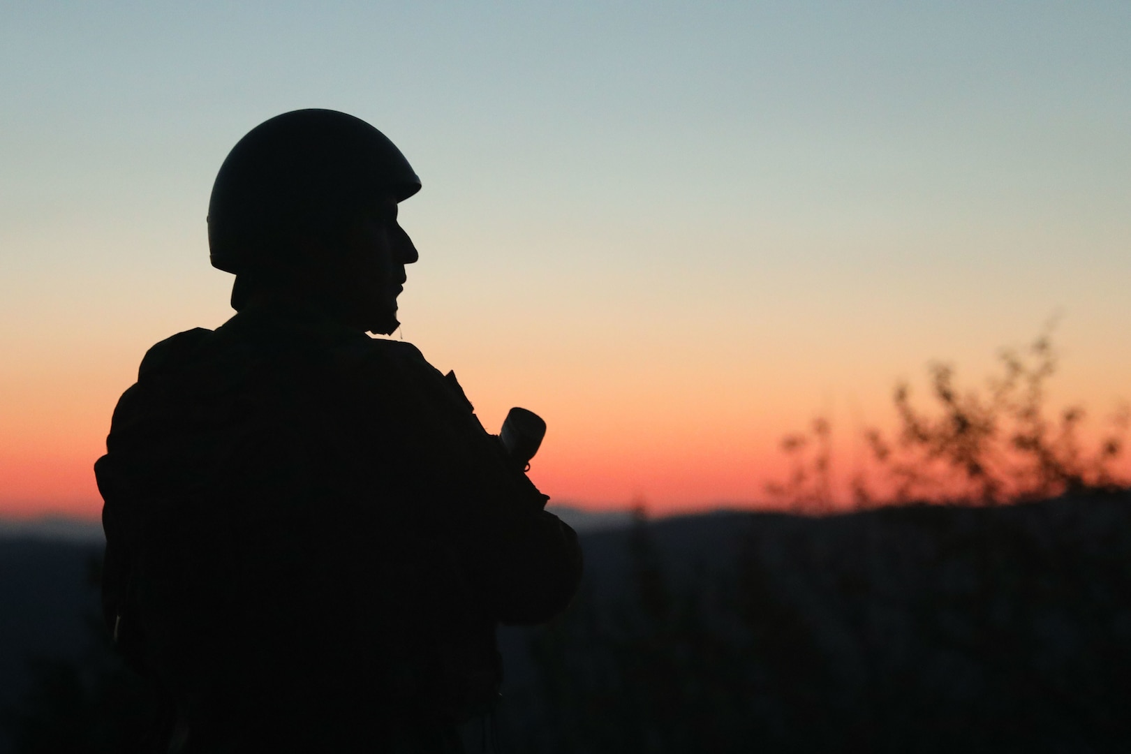 Silhouetted Soldier stands in front of sunset at Camp Bondsteel, Kosovo