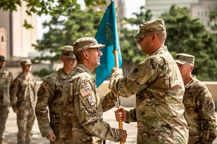 Oklahoma National Guard Maj. Barrett Alexander (left),  incoming commander with the 63rd CST,  receives the unit guidon from Col. Lars Ostervold (right), commander of the 90th Troop Command, during a change of command ceremony at the Oklahoma City Memorial and Museum, Sept. 1.  The passing of the guidon signifies the formal transfer of authority and responsibility of the unit to the new commander.