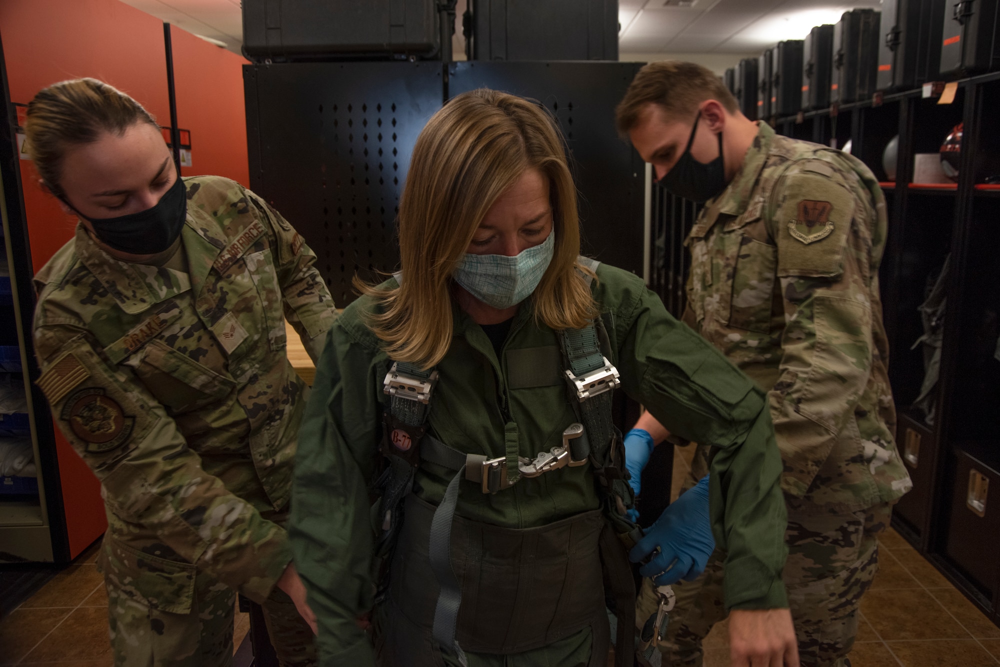 Two Airmen adjusts the waist measurement of the anti-gravity suit for the Boise Mayor.