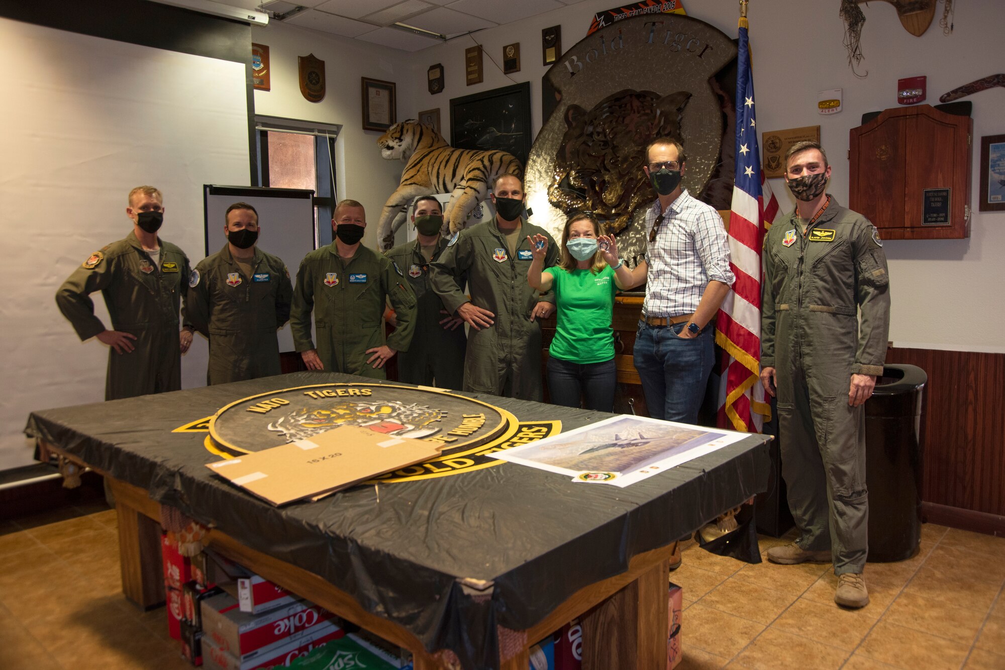 The mayor displays two Air Force coins and pose for a photo with her husband and Airmen.