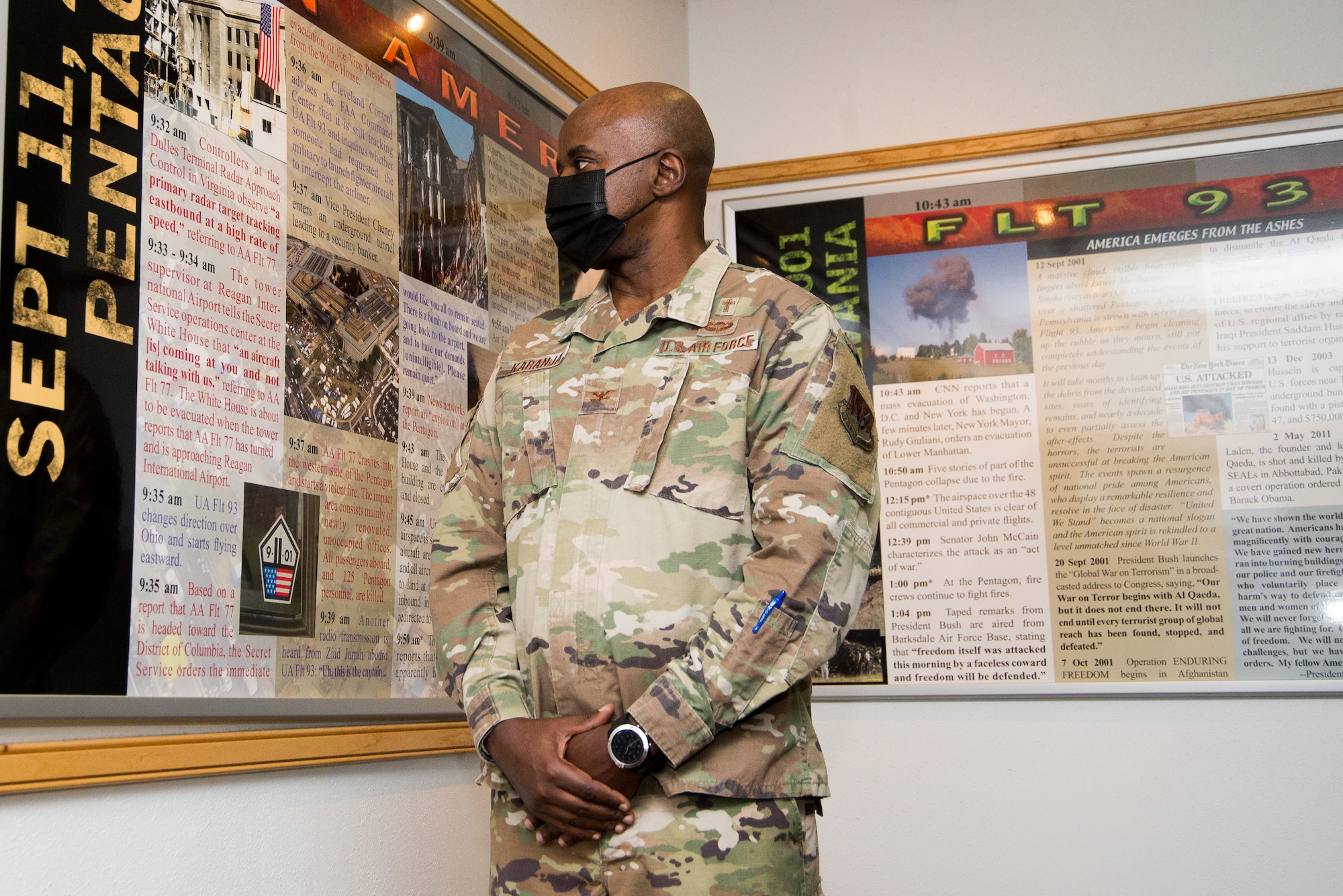 Man in uniform stands next to display.