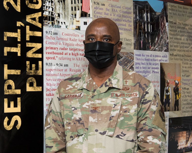 Man in uniform stands next to display.