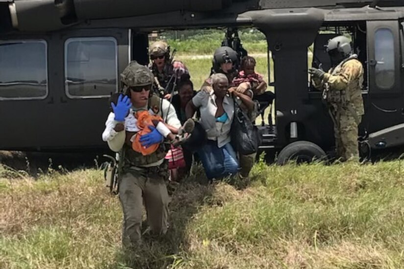 An airman carries an injured child from a helicopter.