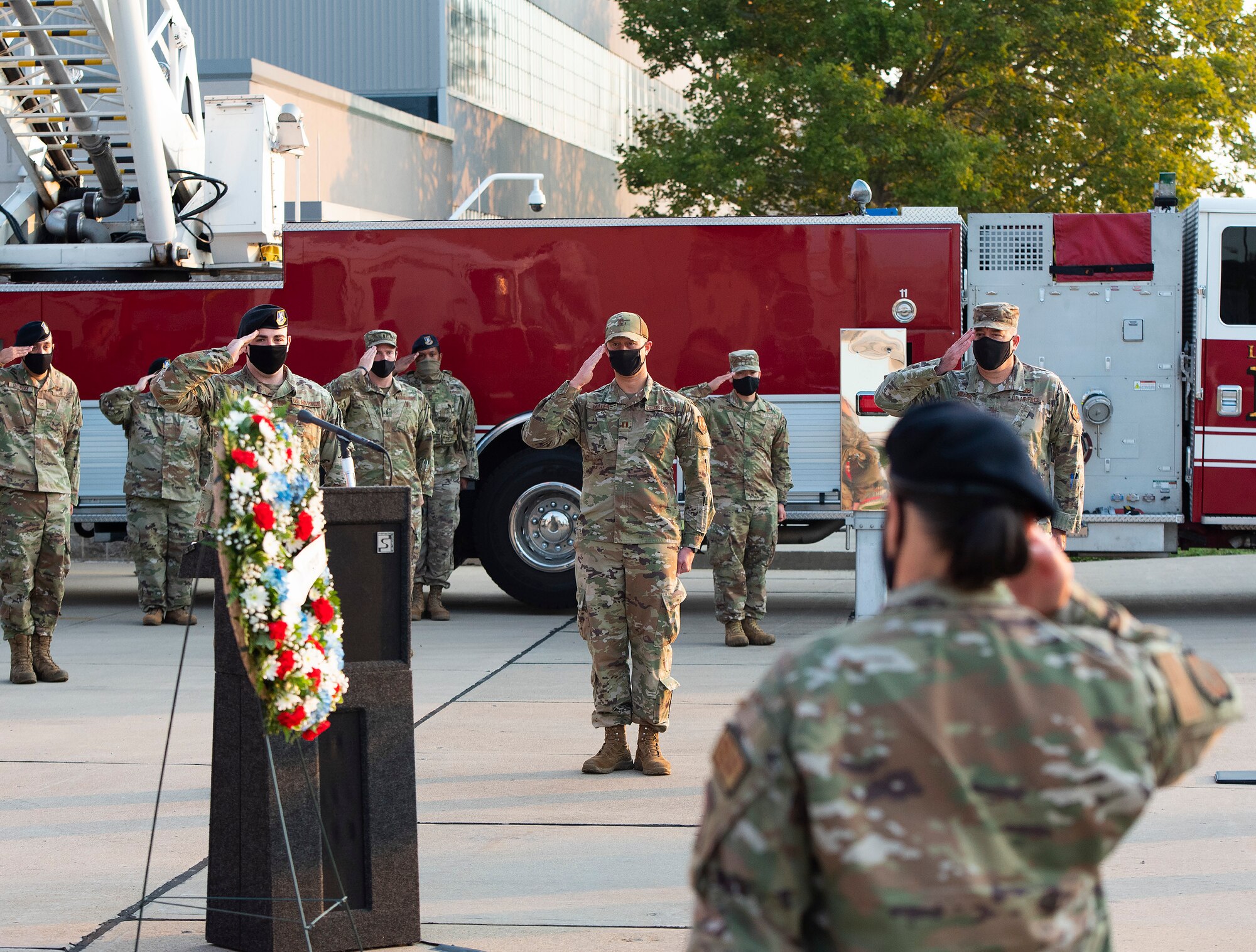 Airmen attending the ceremony Sept. 10, 2021, commemorating the 20th anniversary of the 9/11 attacks salute during the playing of taps after a wreath-laying at Fire Station One on Wright-Patterson Air Force Base, Ohio. Firefighters, Explosive Ordnance Disposal Flight members and base leadership attended the ceremony, which was streamed online for the rest of the Wright-Patt community. (U.S. Air Force photo by R.J. Oriez)