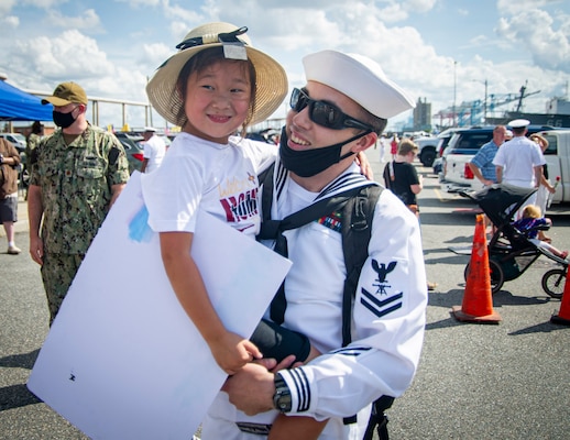 Fire Control Technician 1st Class Patrick Martin, assigned to the Virginia-Class fast-attack submarine USS New Mexico (SSN 779), holds his daughter during the boat’s homecoming at Naval Station Norfolk, Sept. 15, 2021.