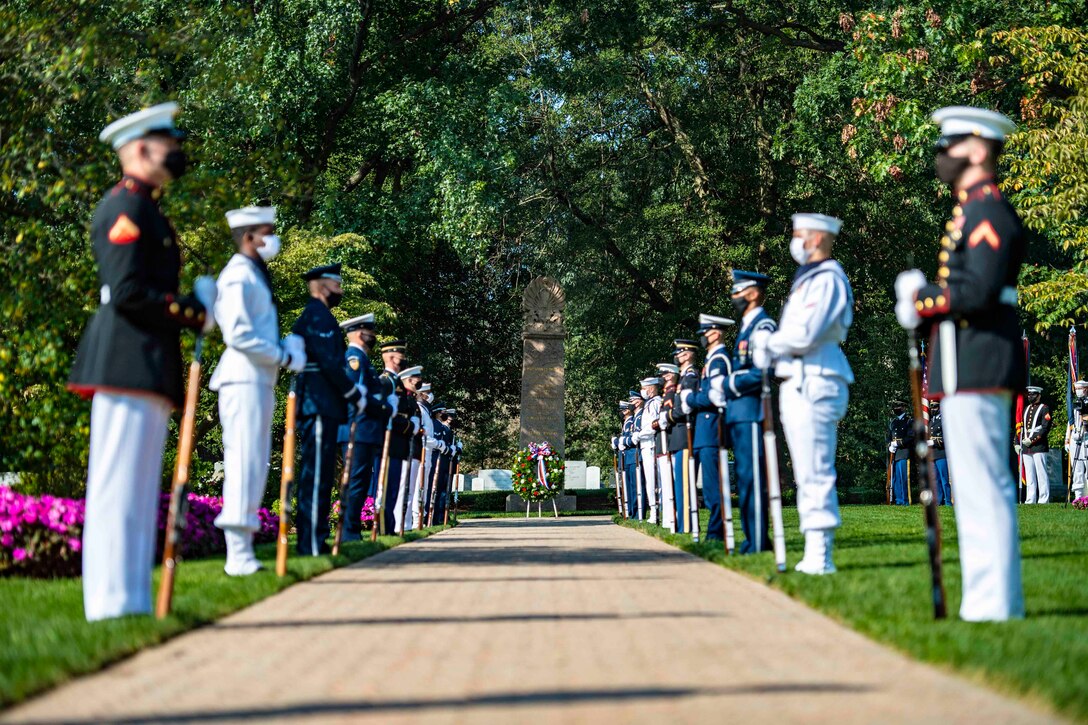 Service members stand in formation along a pathway.