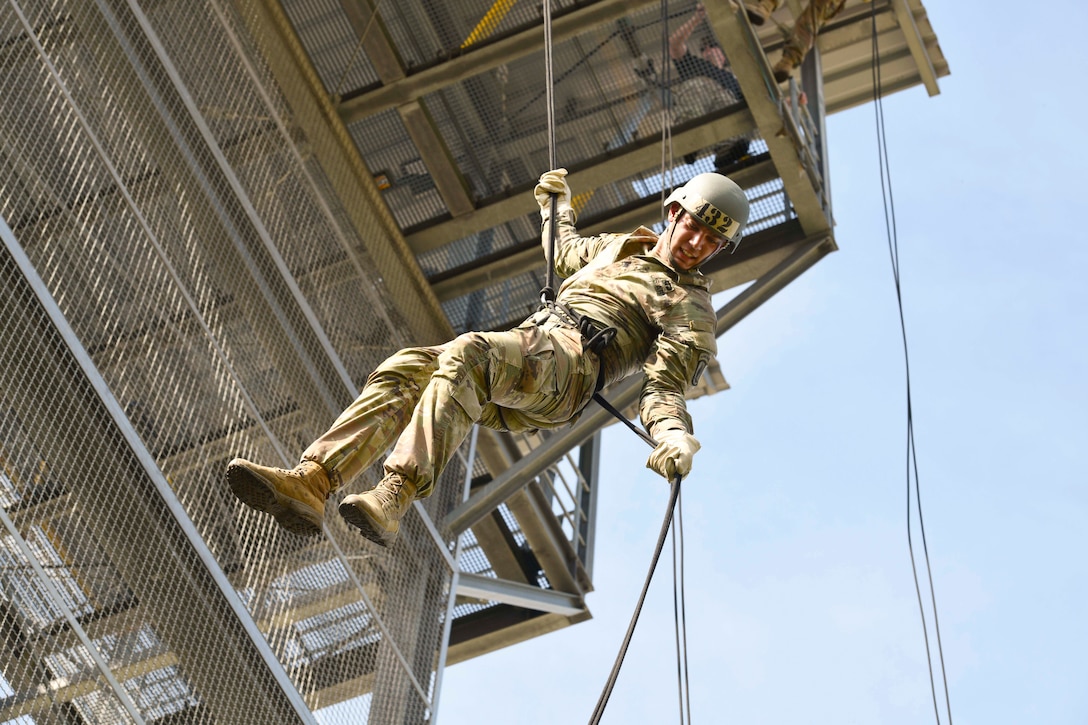 A soldier rappels down a tower.